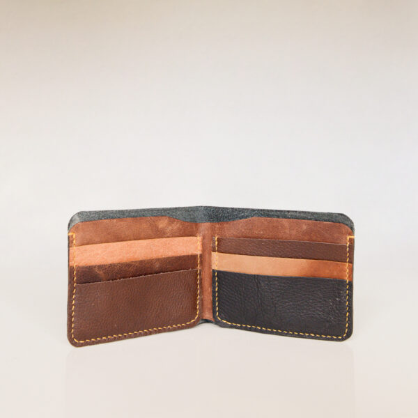 Open view of bifold wallet showing 6 card slots and a compartment for notes. Made from reclaimed and upcycled leather in tan, brown and black