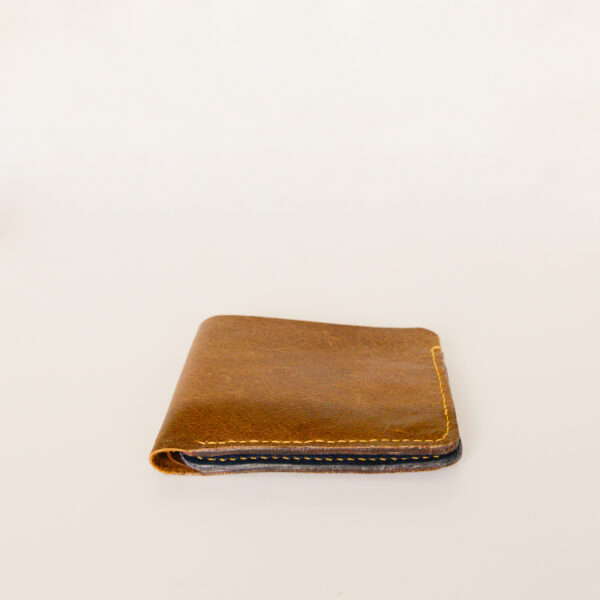 Side view of tan leather bifold wallet made from leather upcycled and reclaimed from old sofas. Hand stitched with yellow linen thread
