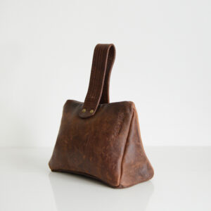 Side view of triangular door stop with handle made from reclaimed and repurposed leather