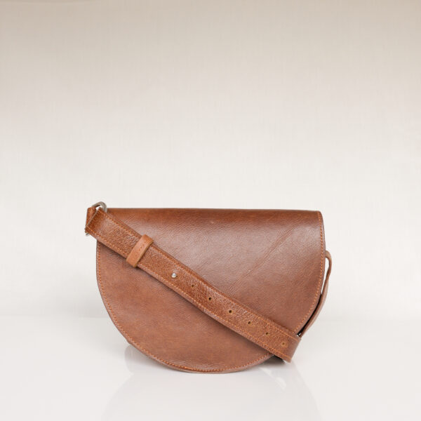 Rear view of handmade tan leather shoulder bag with adjustable strap laid over back of bag