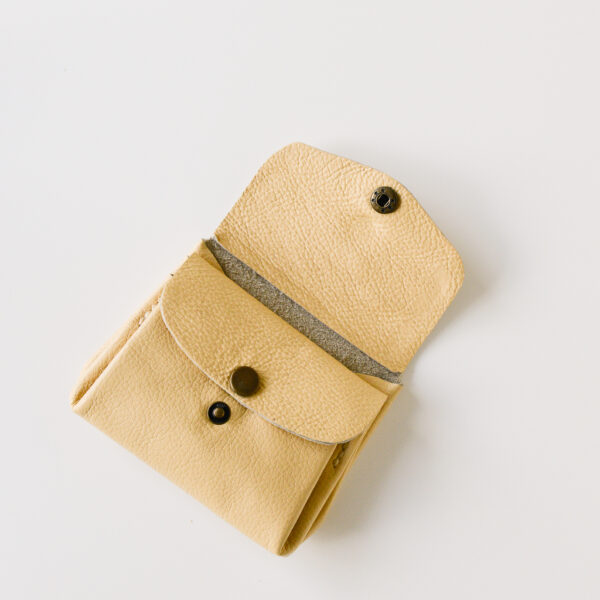 Yellow leather wallet with antique brass poppers. Open to show one pocket and internal poppered section