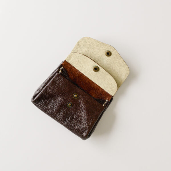 Dark brown leather wallet with contrasting cream leather on the inside of the pockets. Open to show all 3 internal sections
