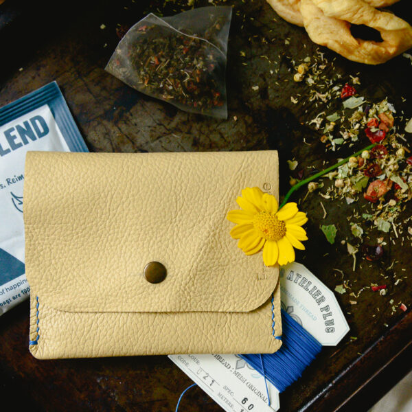 Yellow leather pouch made from reclaimed and recycled leather with black popper closure and stitched with blue linen thread