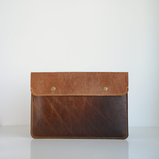 Tan leather laptop case with brass poppers and yellow linen stitching